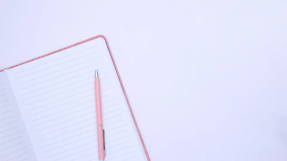 Notizbuch und Lesebrille auf einem Schreibtisch